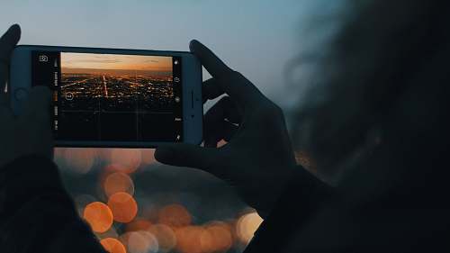 picture person capturing photo of city using iPhone during orange sunset iphone